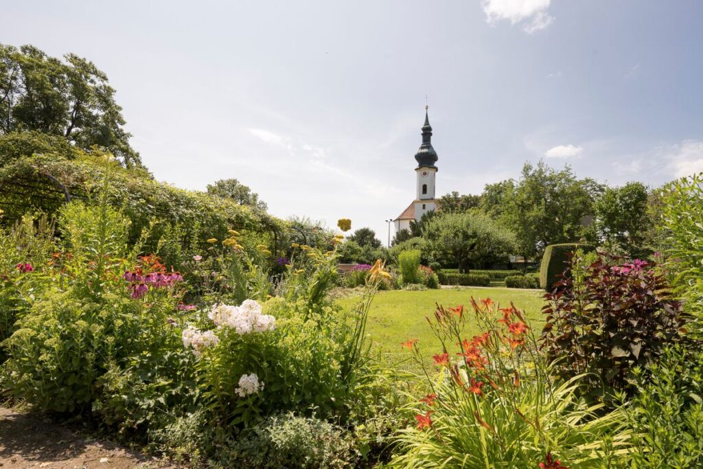 Immobilienmakler Starnberg: Blick zwischen Büschen auf eine Kirche