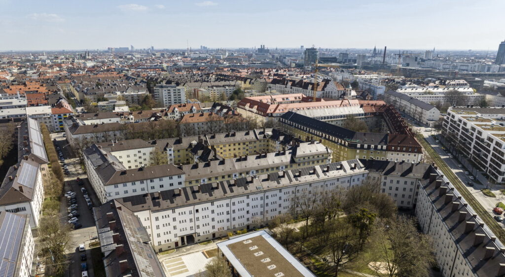 Immobilienmakler Neuhausen: Eine beeindruckende Luftaufnahme zeigt ein städtisches Viertel mit geschlossenen Wohnblocks, begrünten Innenhöfen und historischen Dächern.